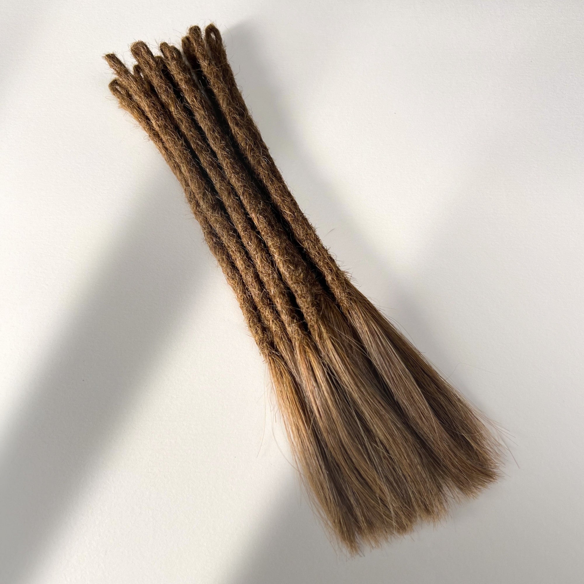 Full view of temporary single-ended straight loc extensions with open ends in Warm Golden Brown.