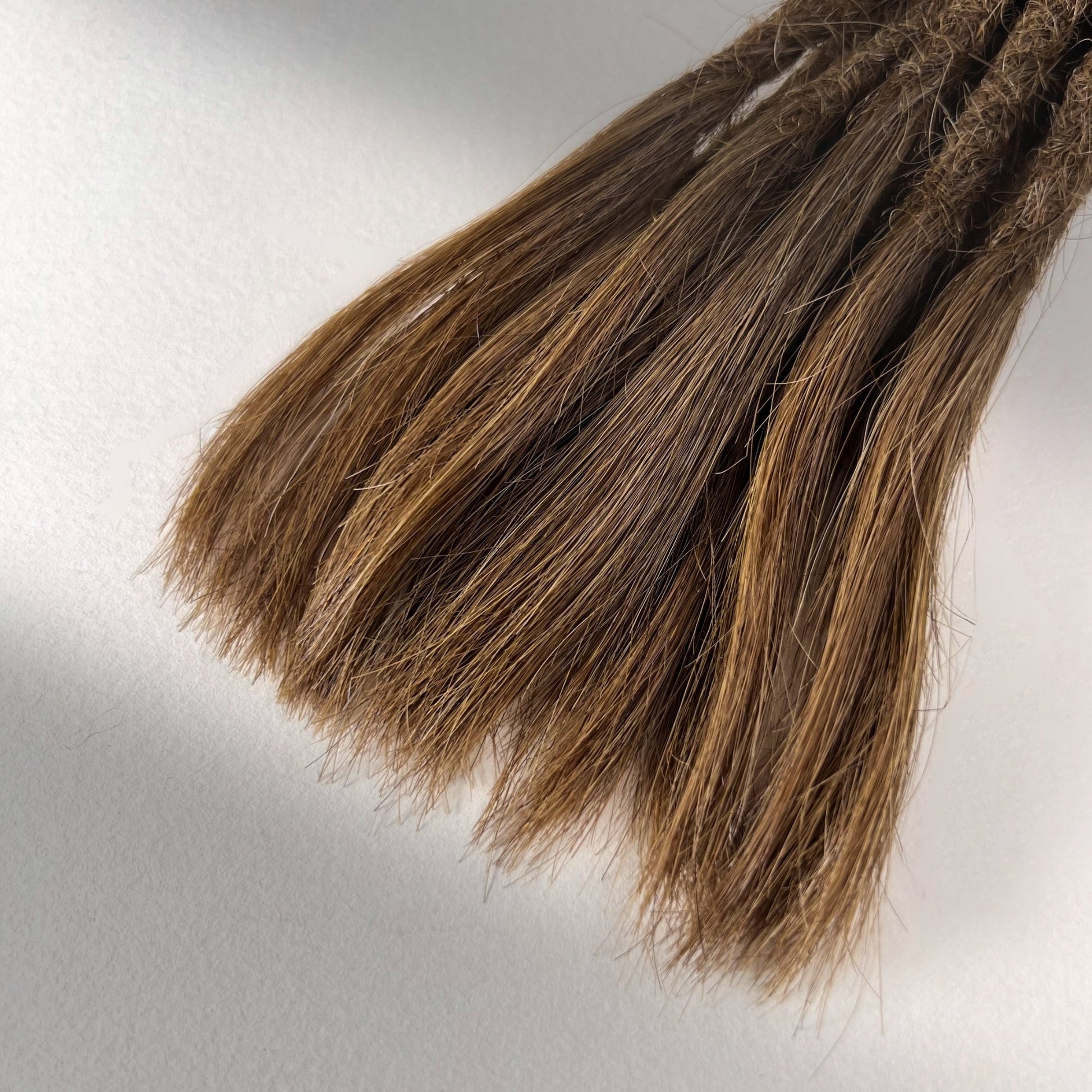 Tip detail of straight loc extensions with open ends in Warm Golden Brown.