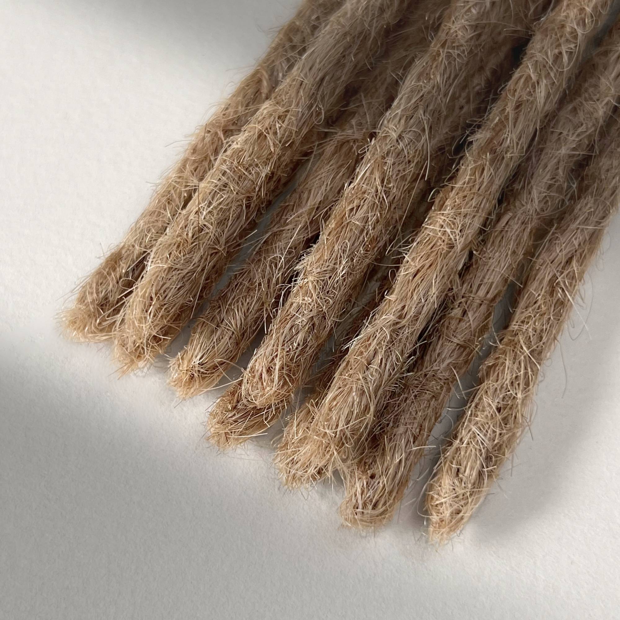 Tip detail of straight loc extensions with blunt ends in Golden Blonde.