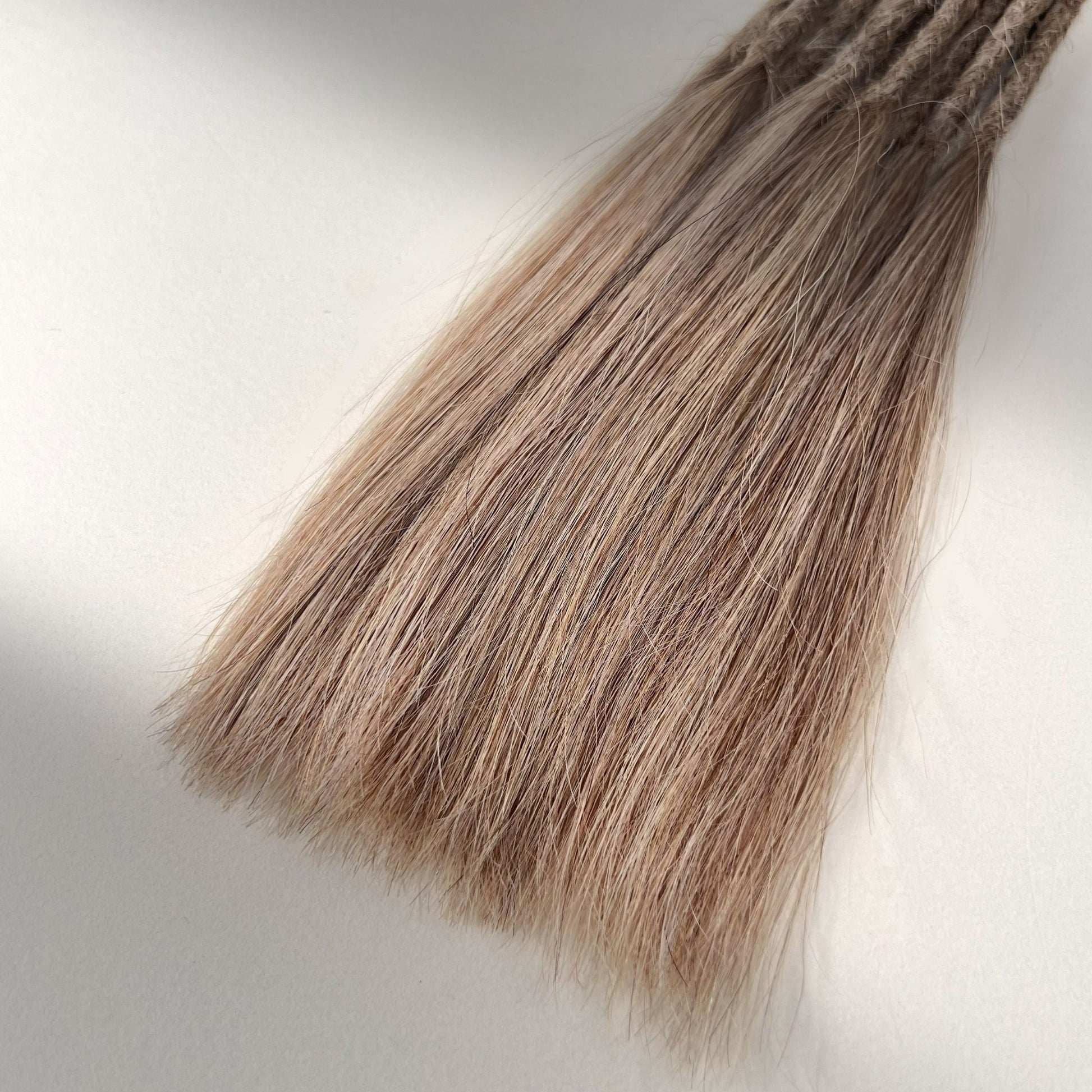 Tip detail of straight loc extensions with long loose ends in Golden Blonde.