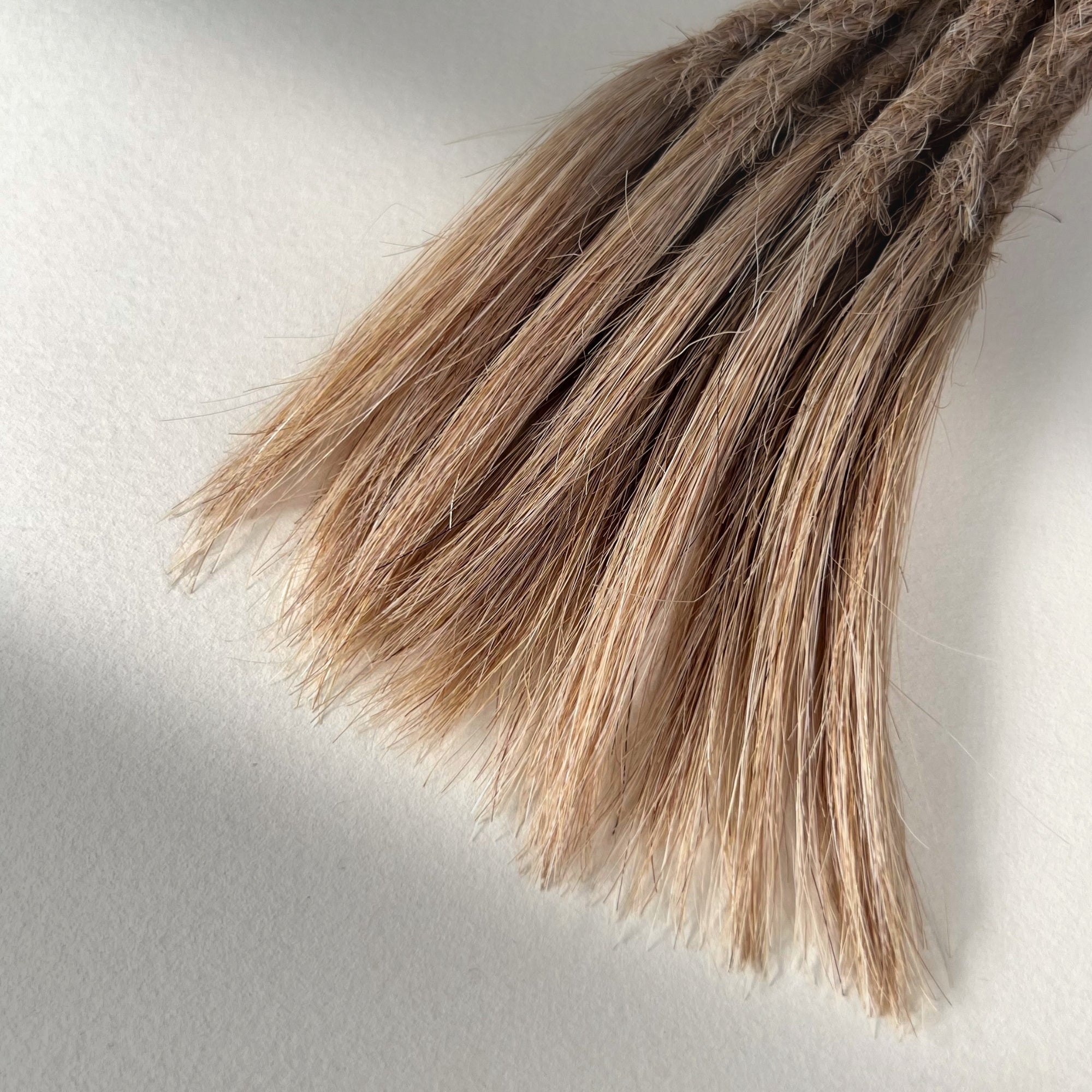 Tip detail of straight loc extensions with open ends in Golden Blonde.