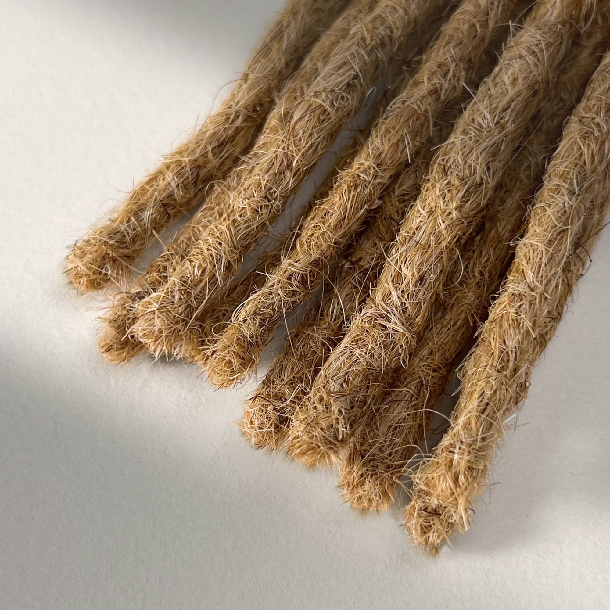 Tip detail of straight loc extensions with blunt ends in Warm Beige Blonde.