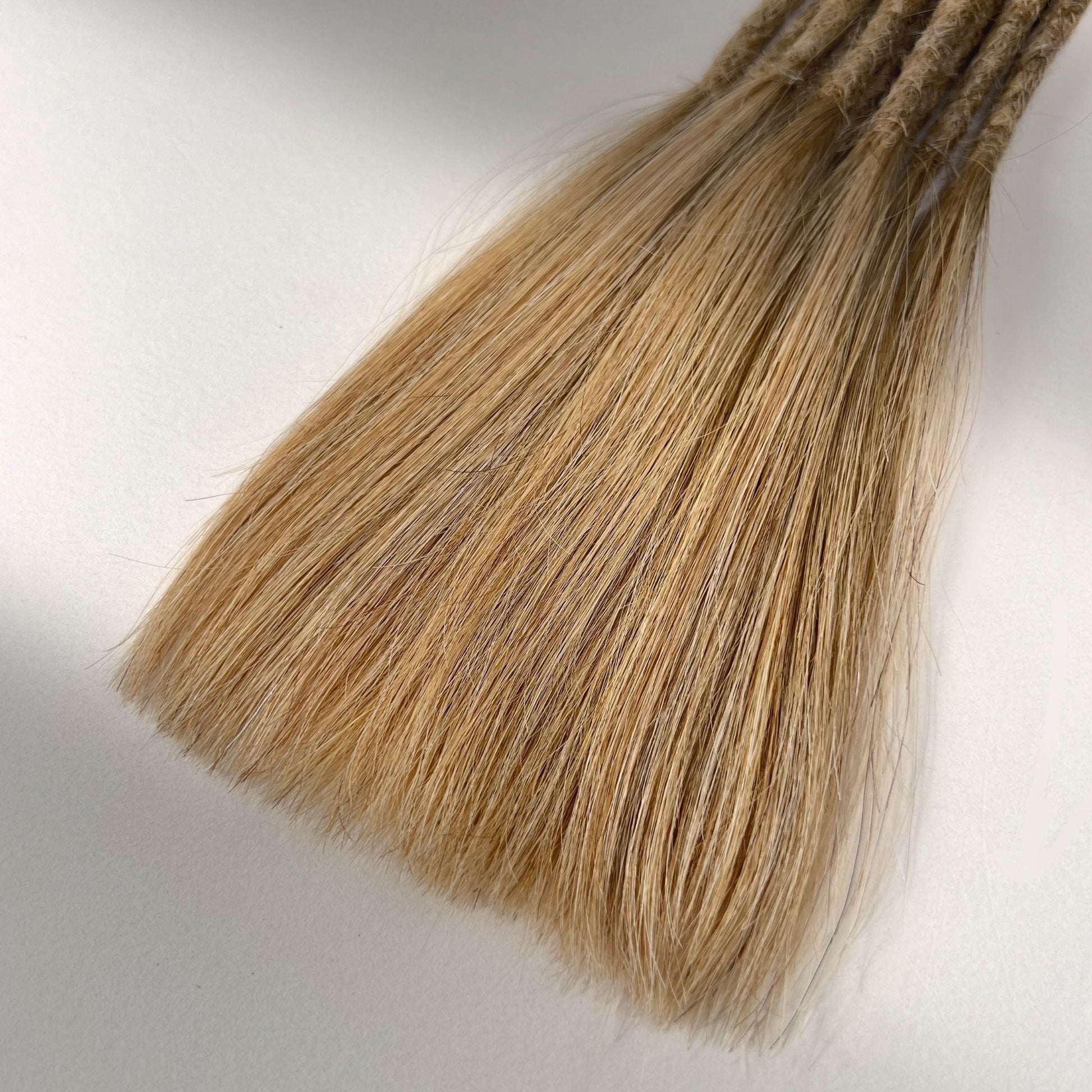 Tip detail of straight loc extensions with long loose ends in Warm Beige Blonde.