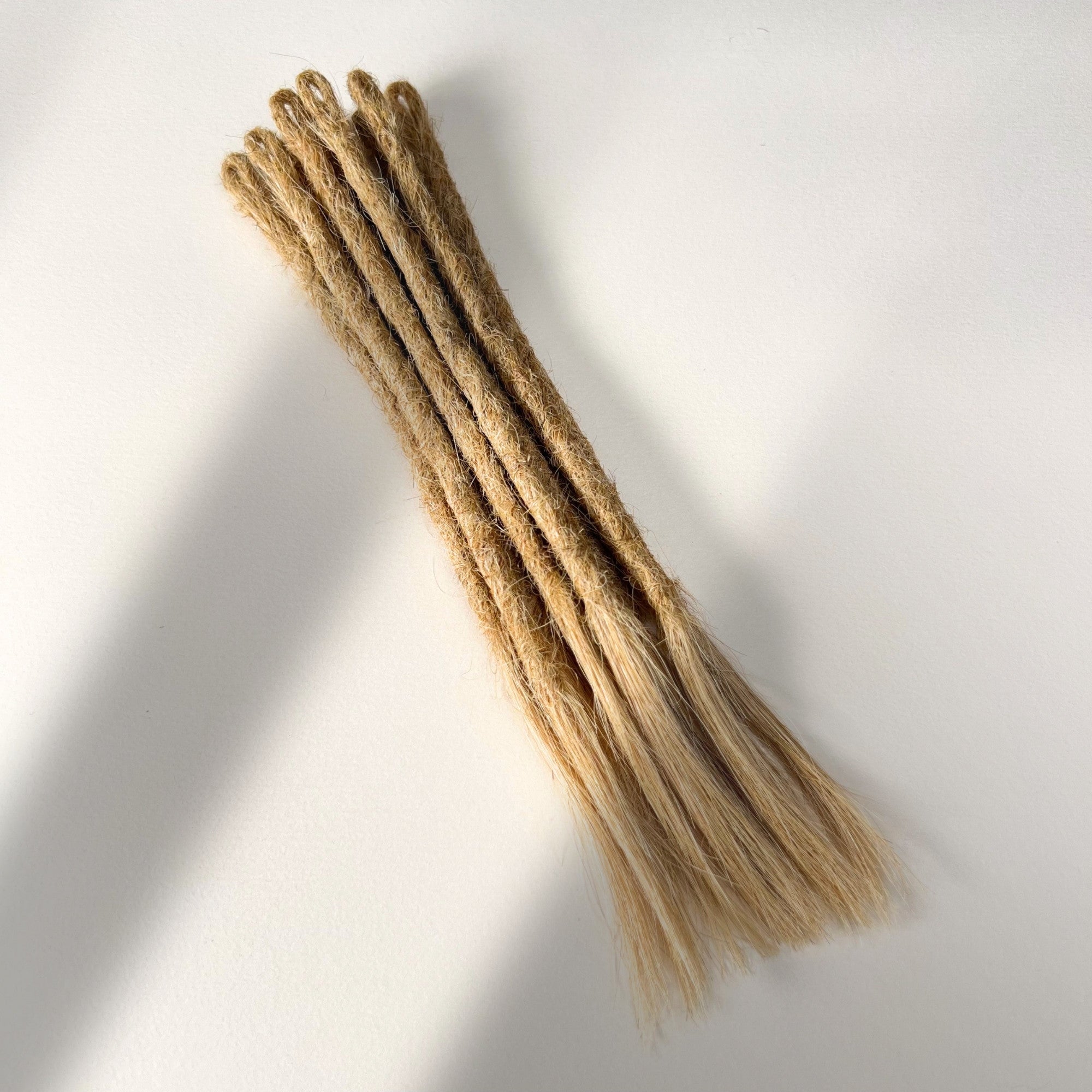 Full view of temporary single-ended straight loc extensions with open ends in Warm Beige Blonde.