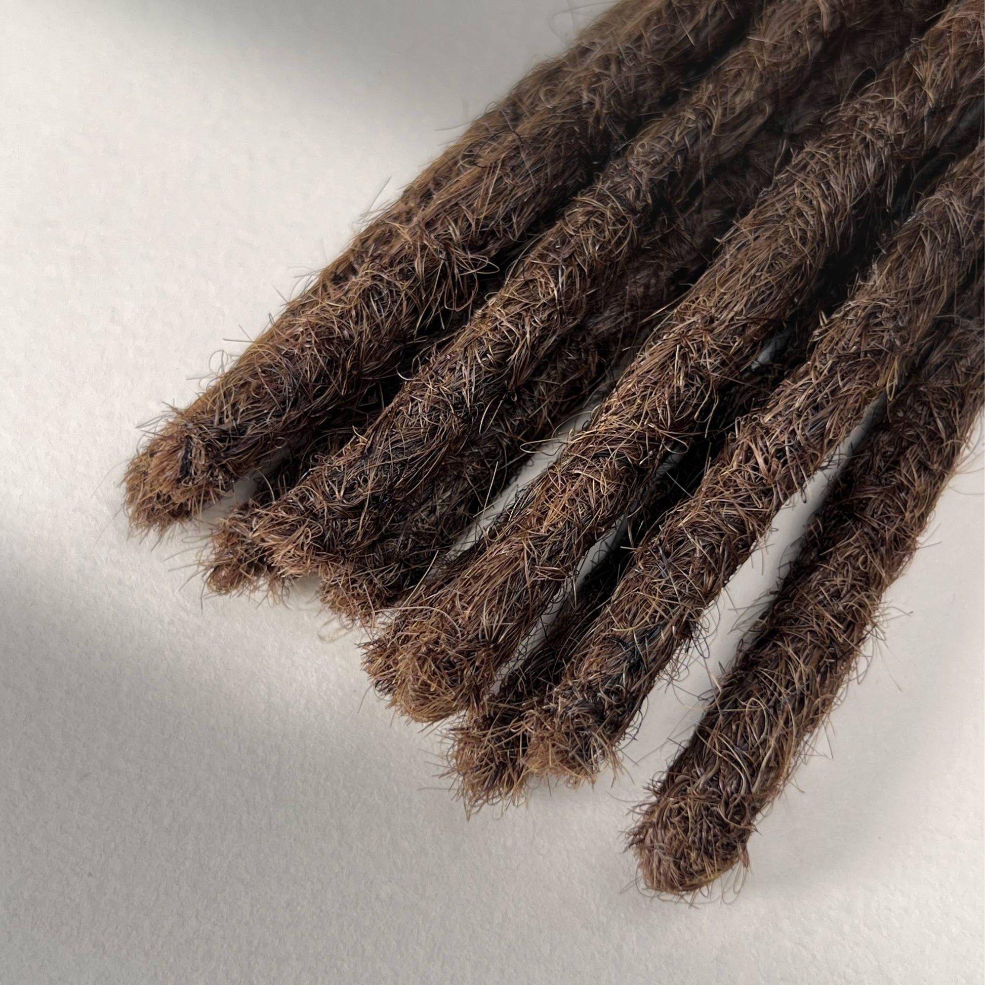 Tip detail of straight loc extensions with blunt ends in Rich Brown.