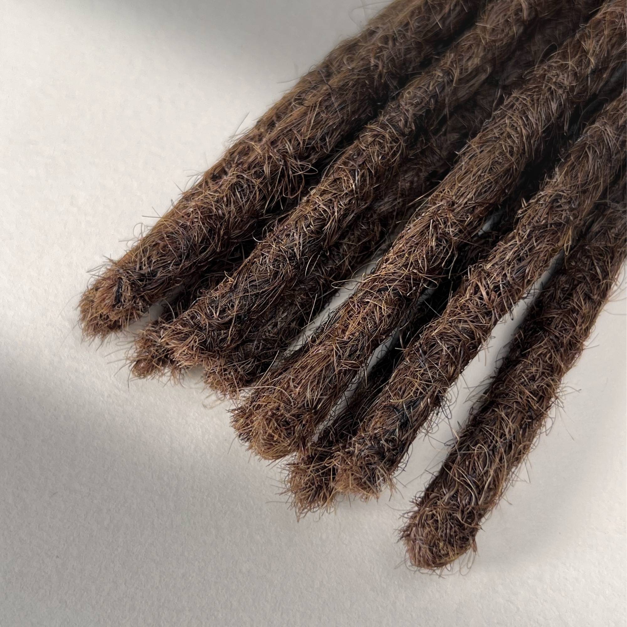 Tip detail of straight loc extensions with blunt ends in Rich Brown.