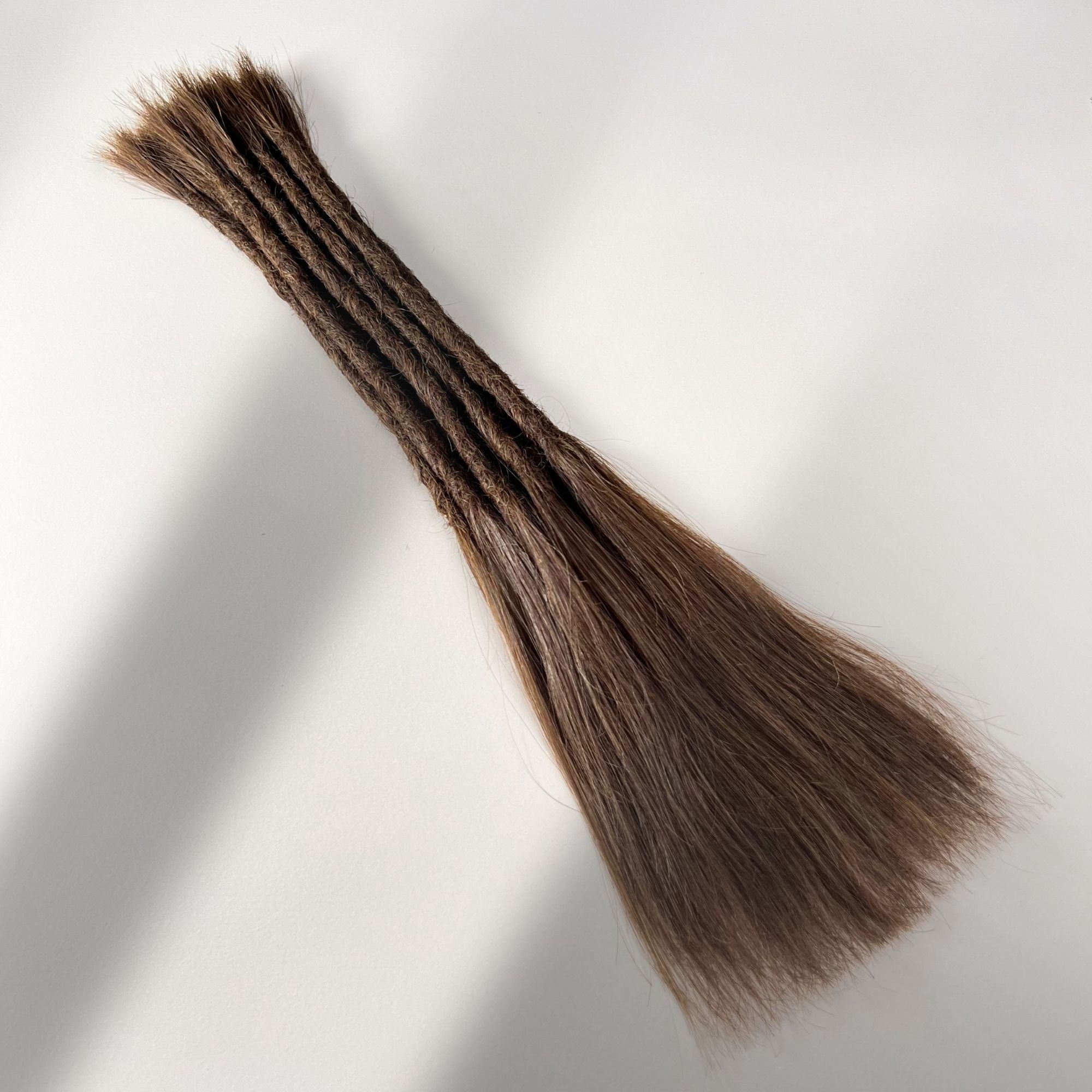 Full view of permanent straight loc extensions with long loose ends in Rich Brown.