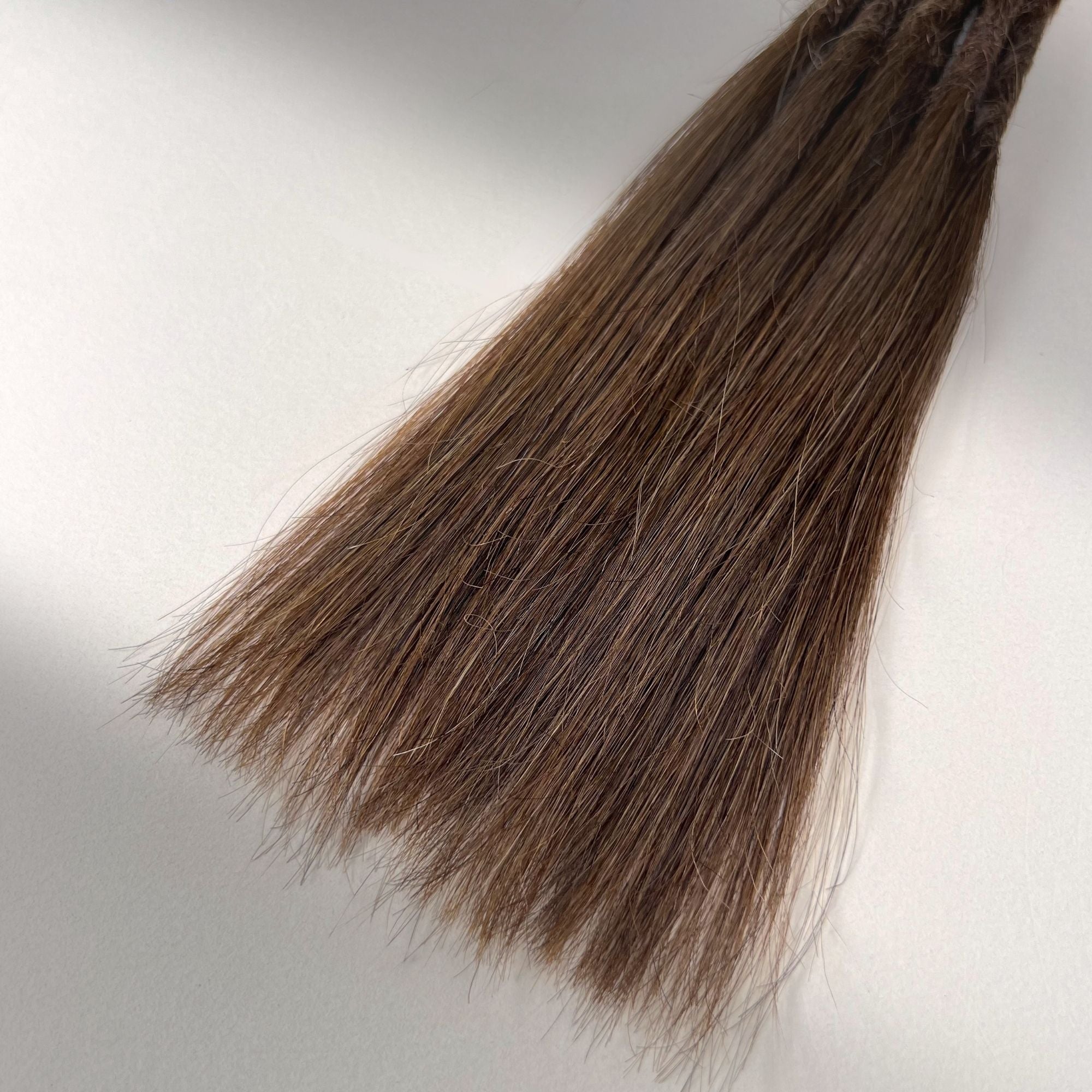 Tip detail of straight loc extensions with long loose ends in Rich Brown.