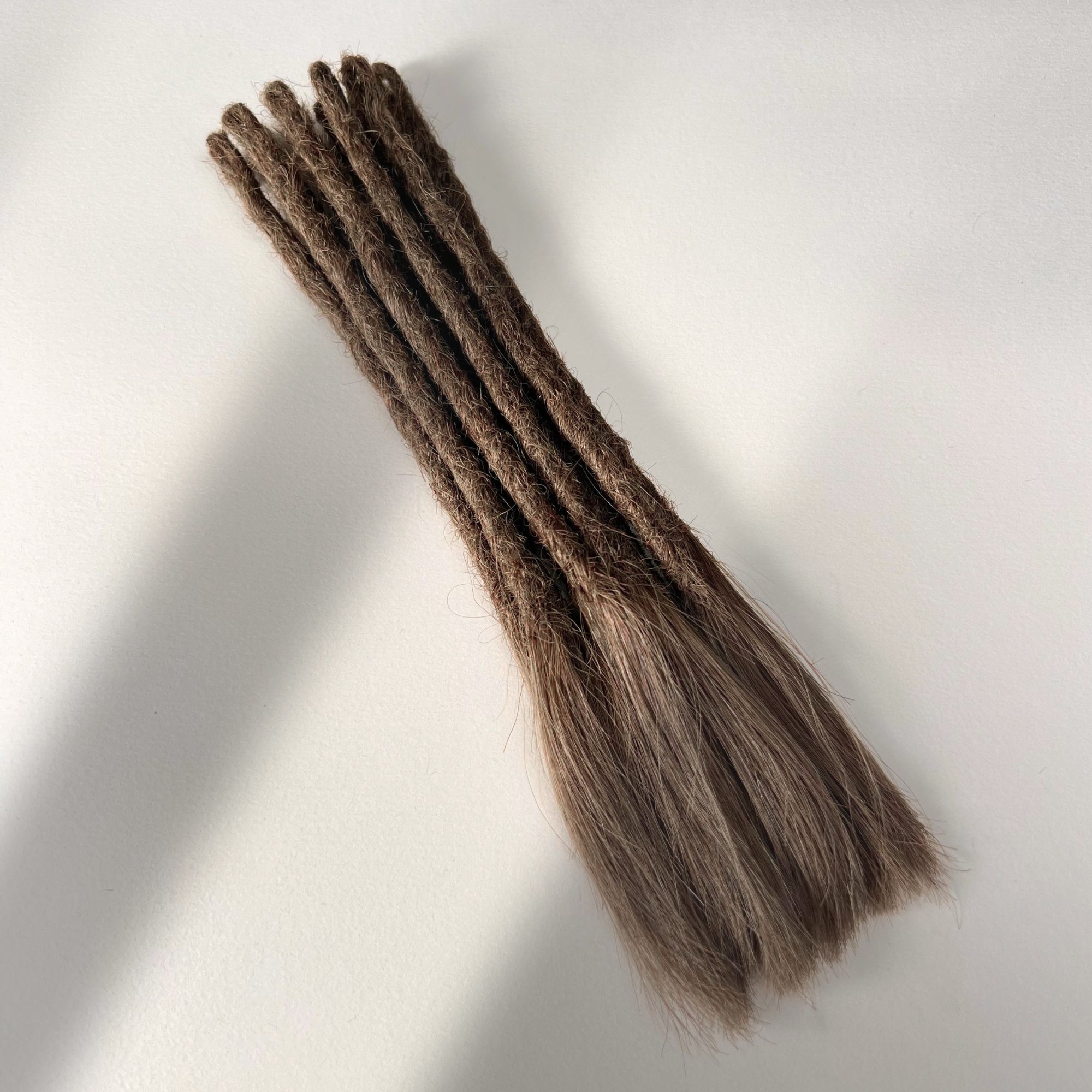 Full view of temporary single-ended straight loc extensions with open ends in Rich Brown.