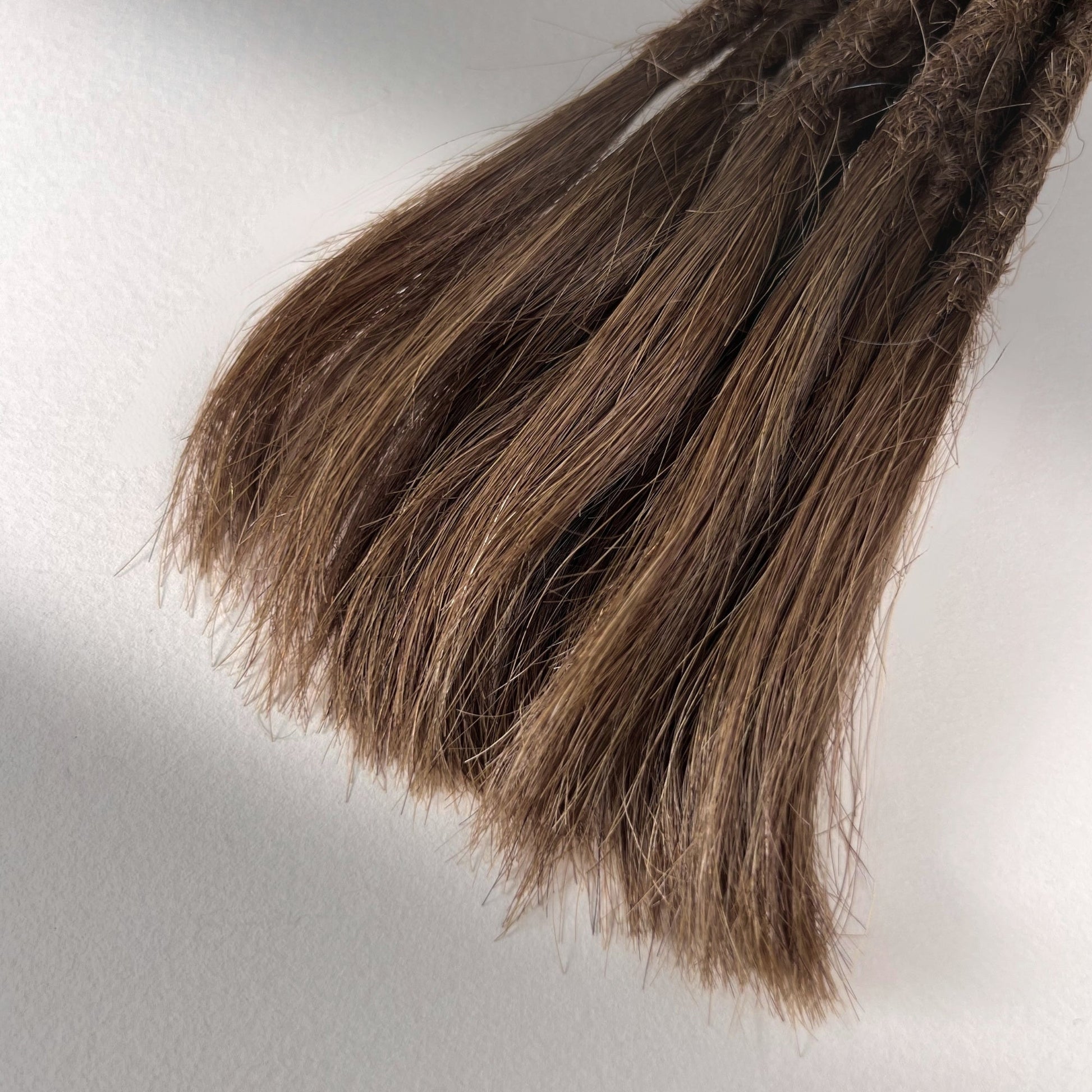 Tip detail of straight loc extensions with open ends in Rich Brown.