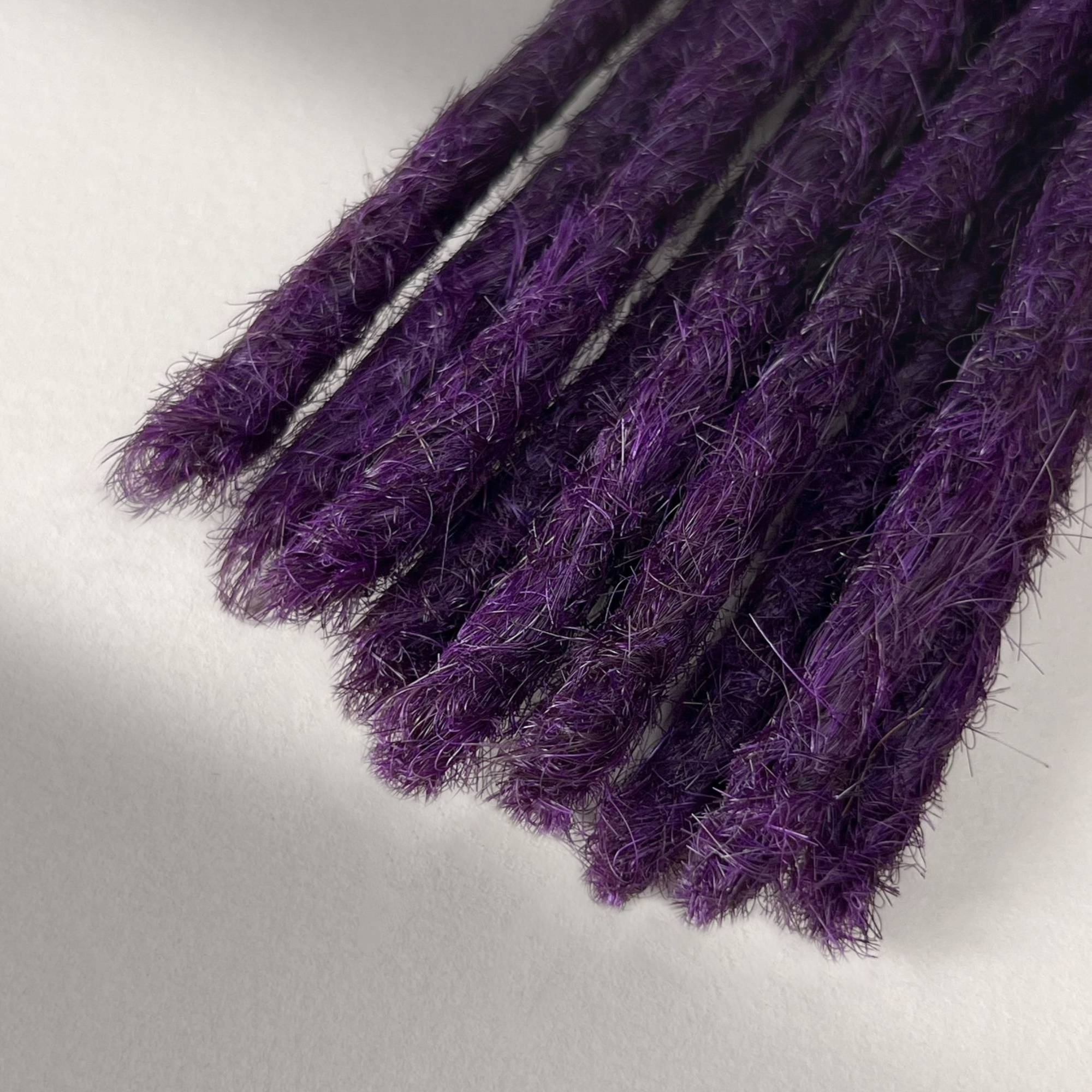 Tip detail of straight loc extensions with blunt ends in Electric Violet.
