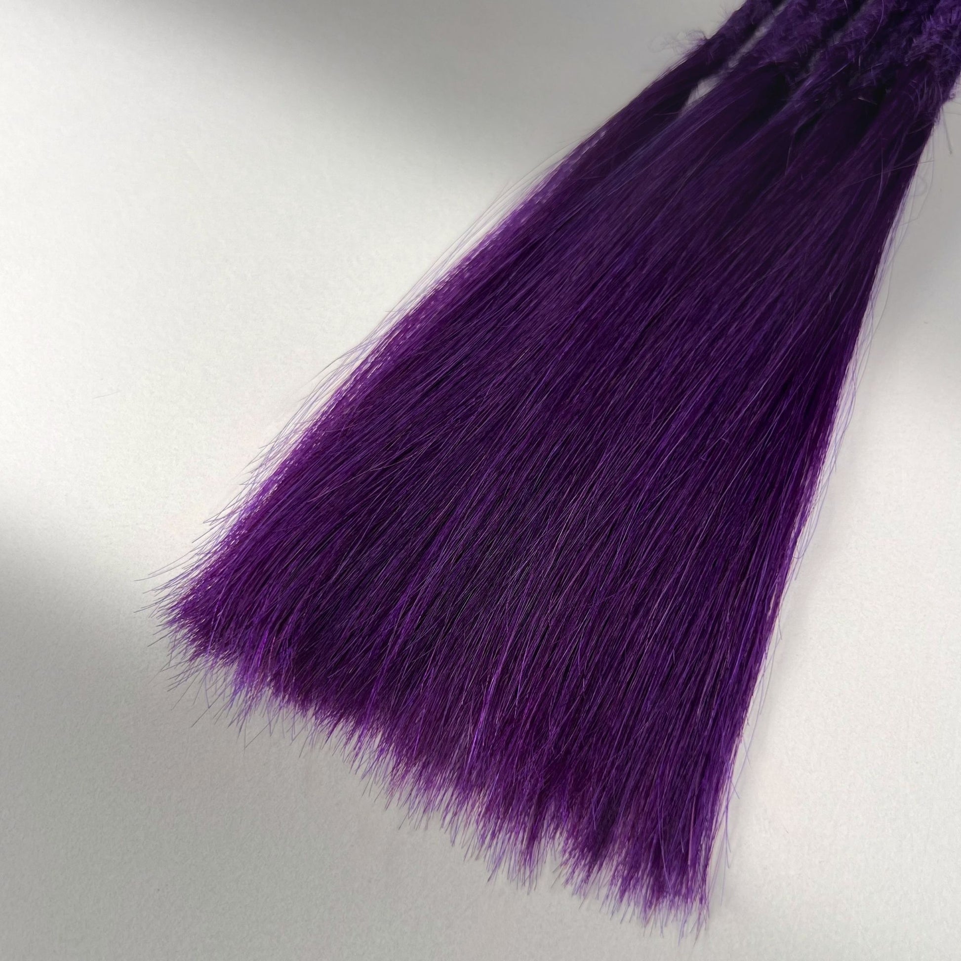 Tip detail of straight loc extensions with long loose ends in Electric Violet.