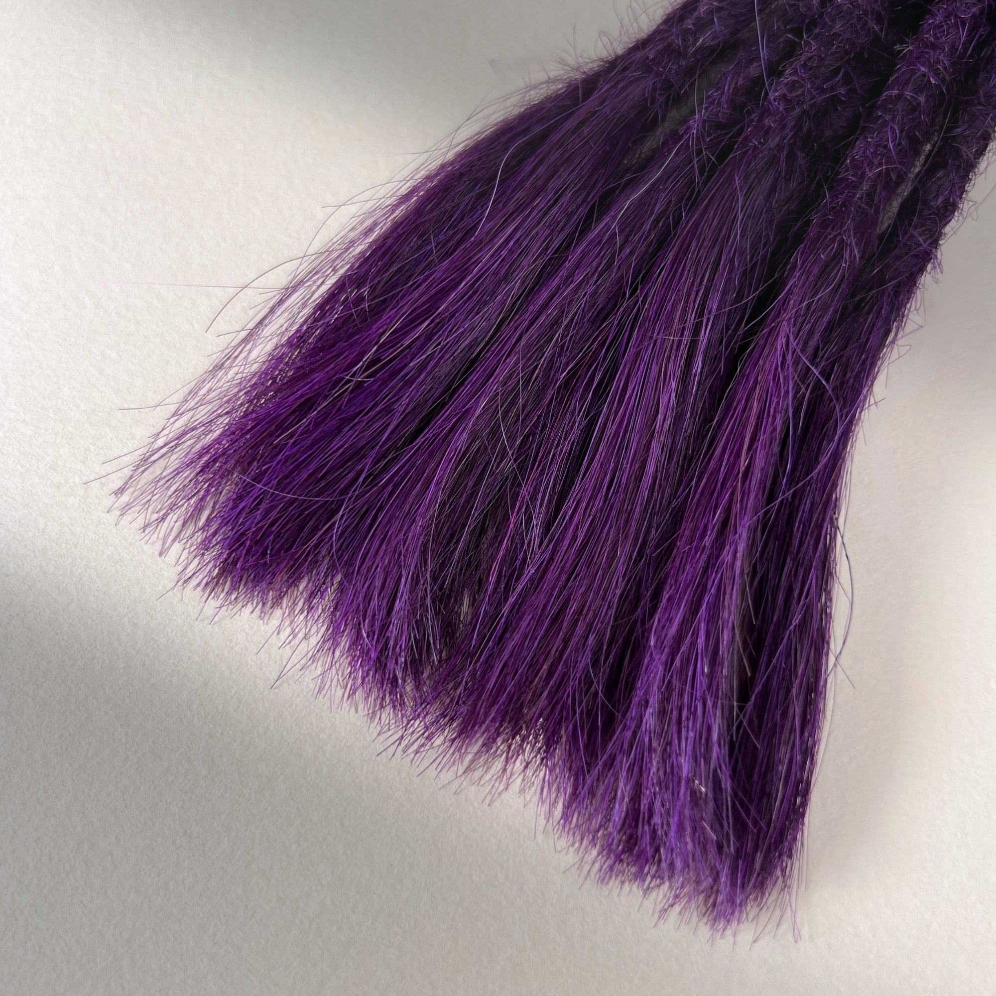 Tip detail of straight loc extensions with open ends in Electric Violet.