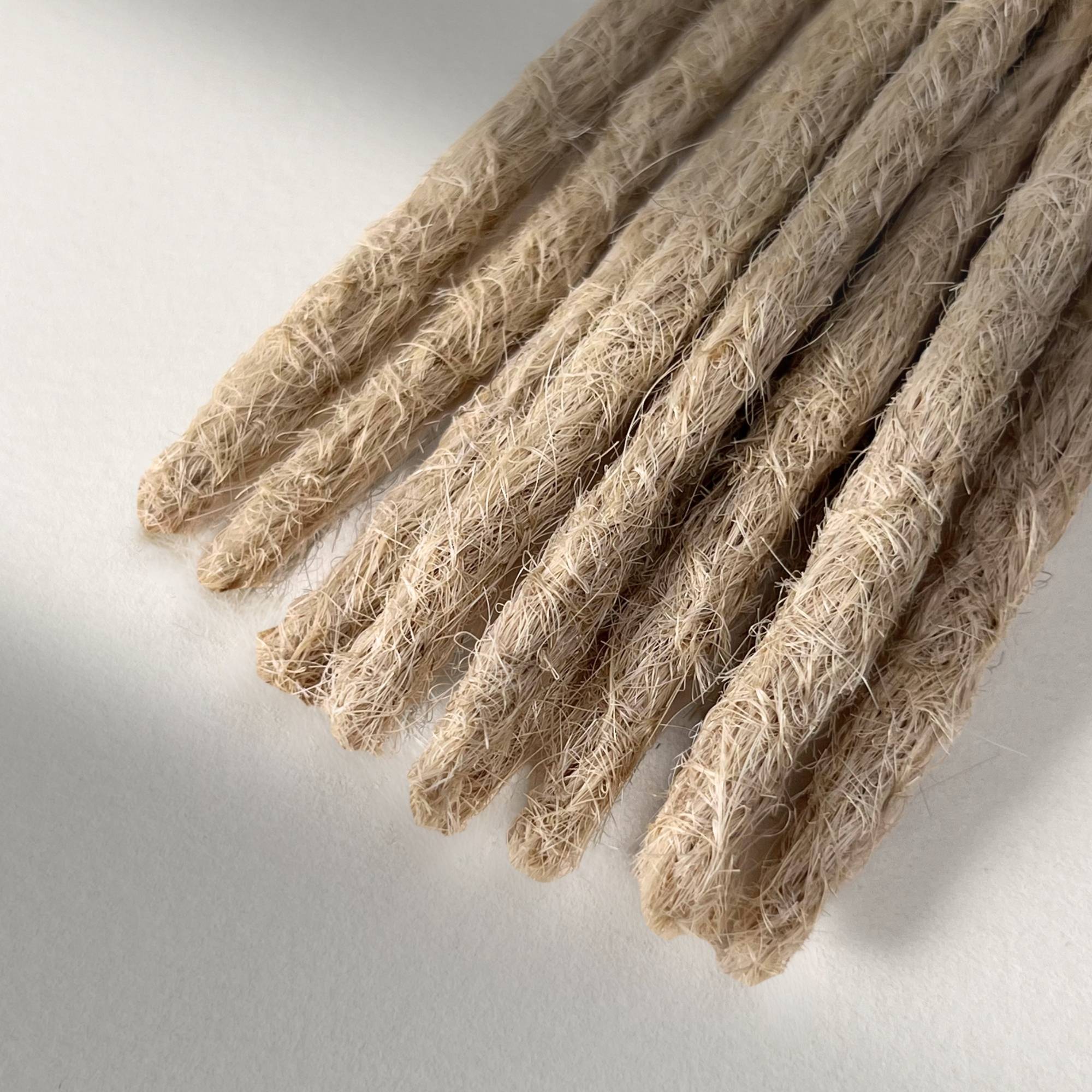 Tip detail of straight loc extensions with blunt ends in Wheat Blonde.