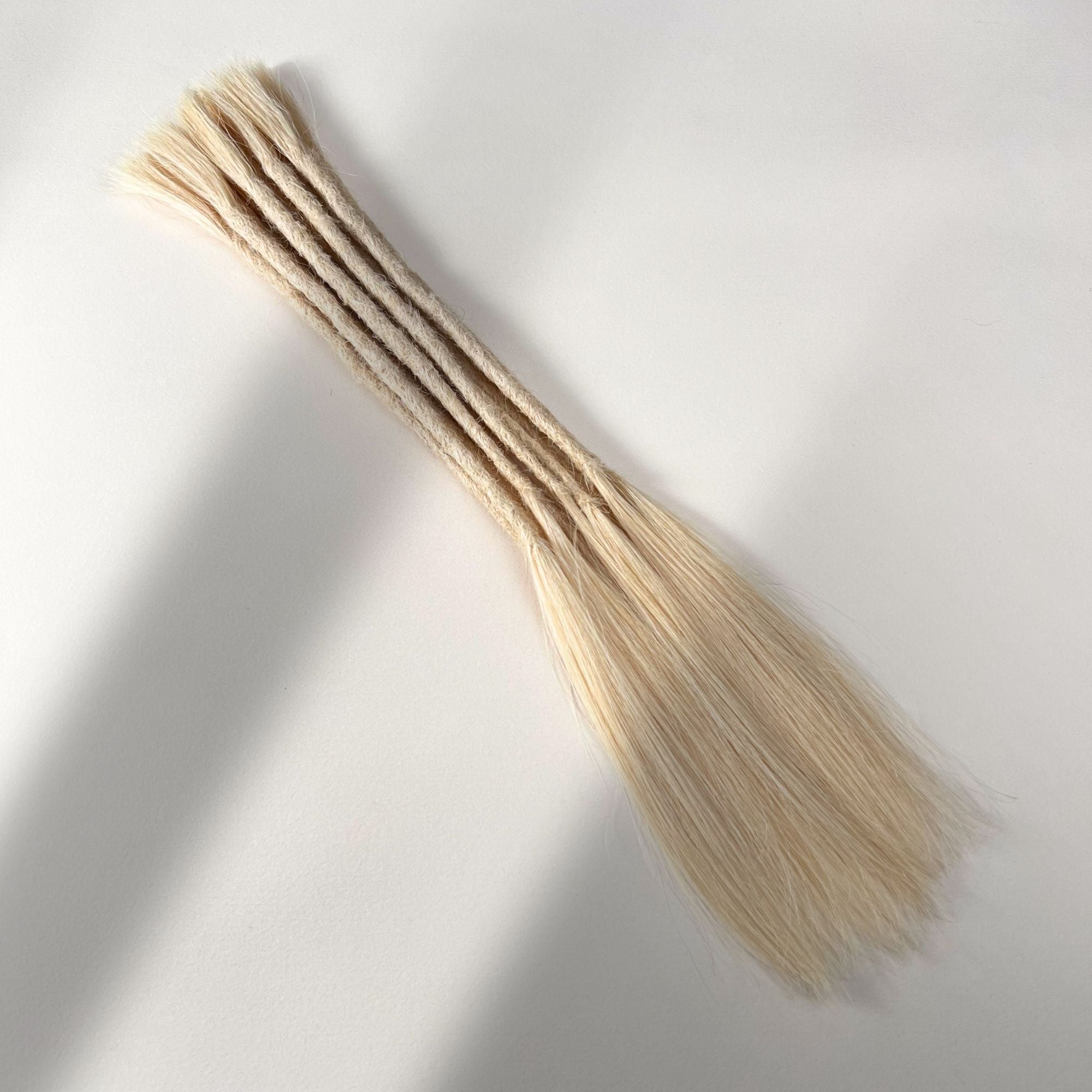 Full view of permanent straight loc extensions with long loose ends in Wheat Blonde.