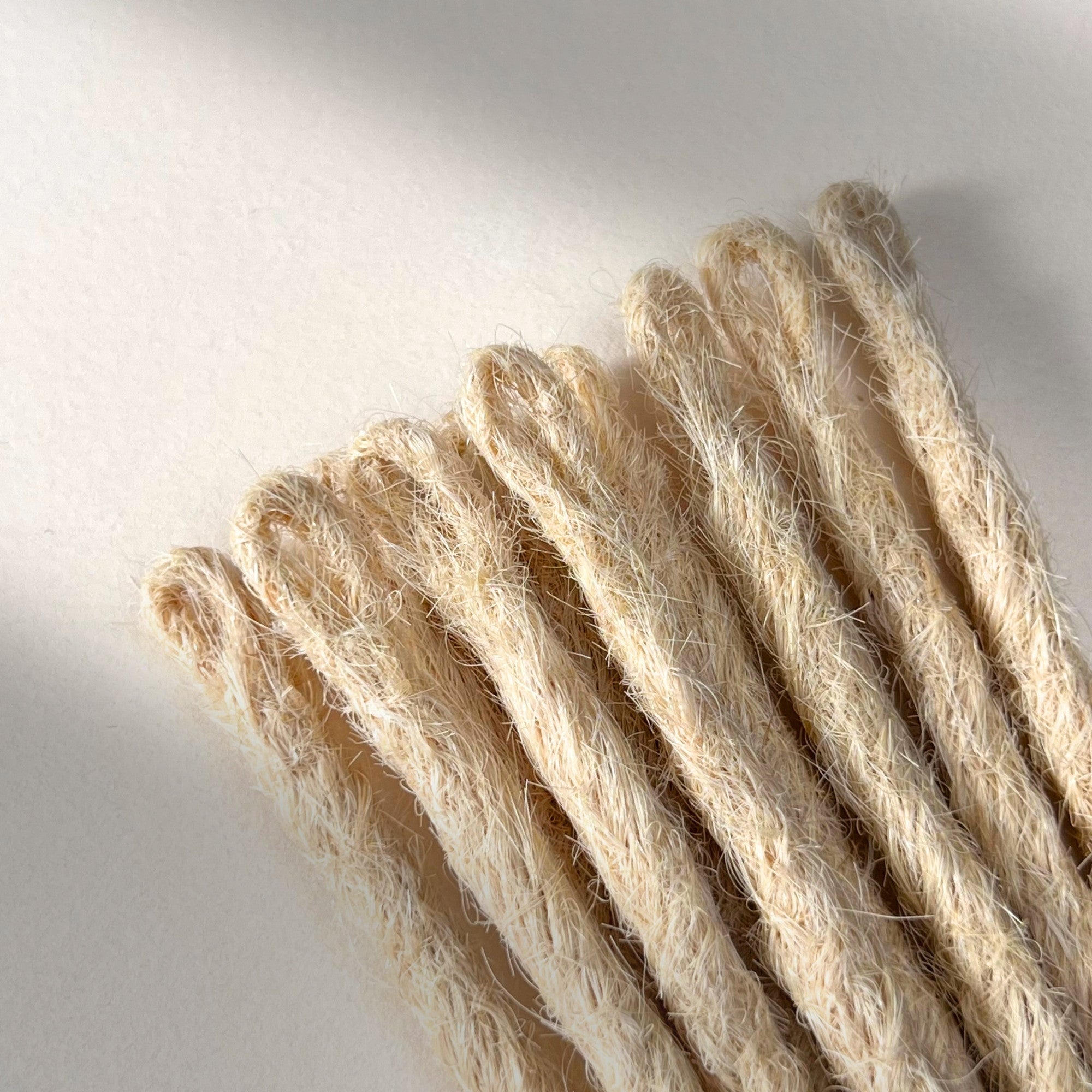 Loop detail of temporary single-ended straight loc extensions with open ends in Wheat Blonde.