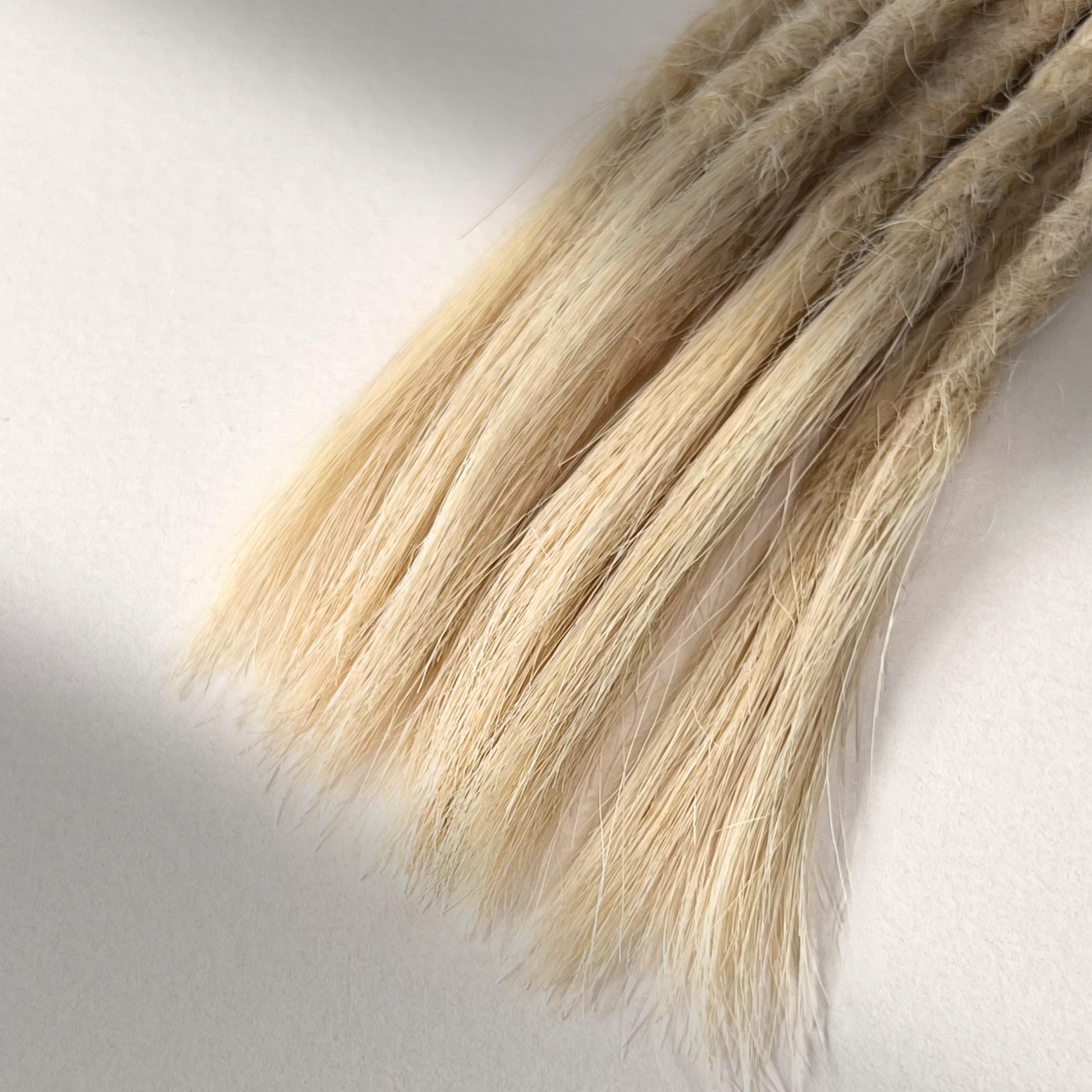 Tip detail of straight loc extensions with open ends in Wheat Blonde.