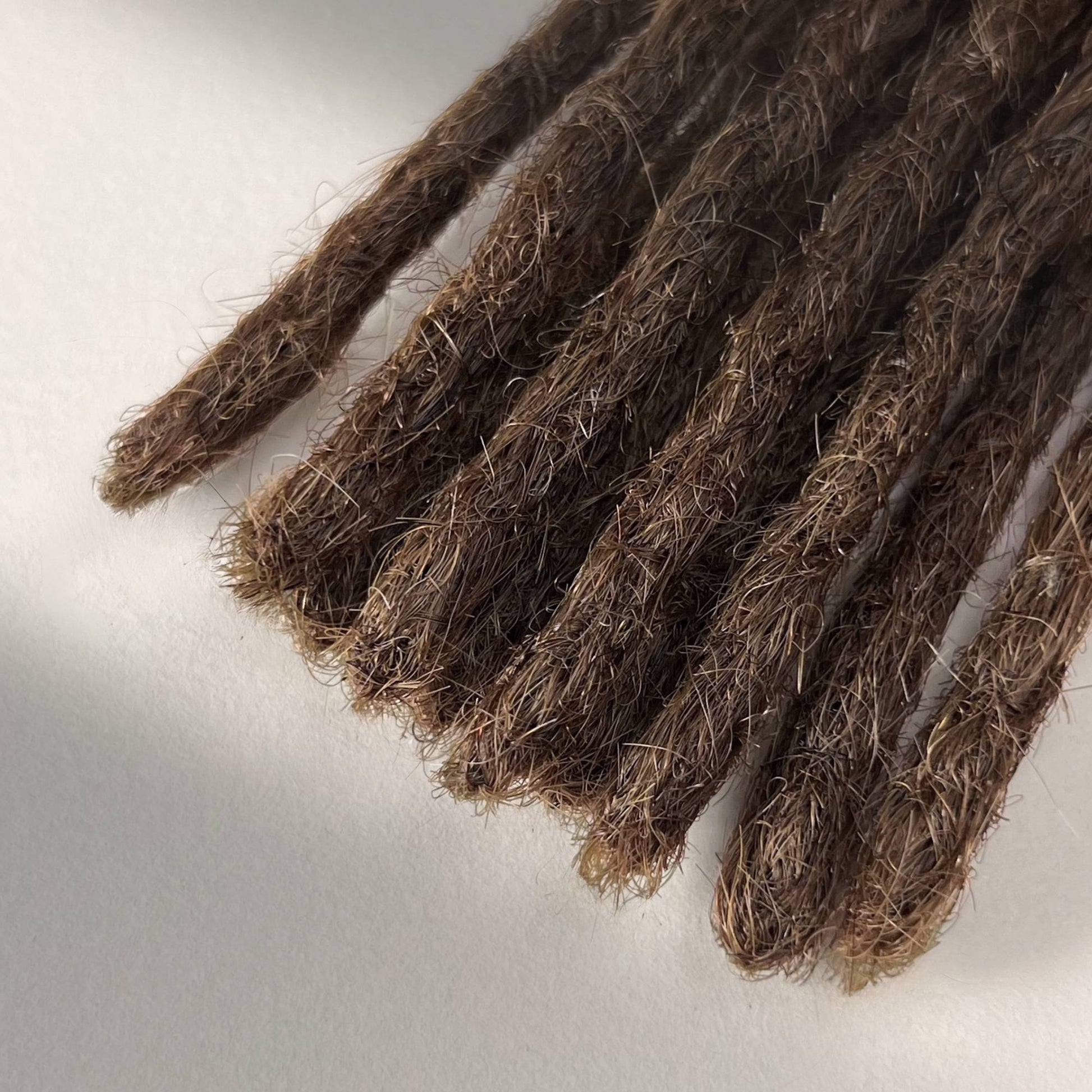 Tip detail of straight loc extensions with blunt ends in Medium Brown.