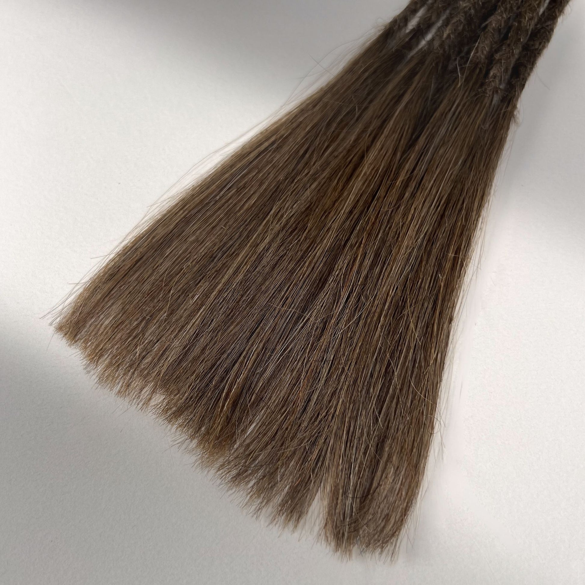 Tip detail of straight loc extensions with long loose ends in Medium Brown.