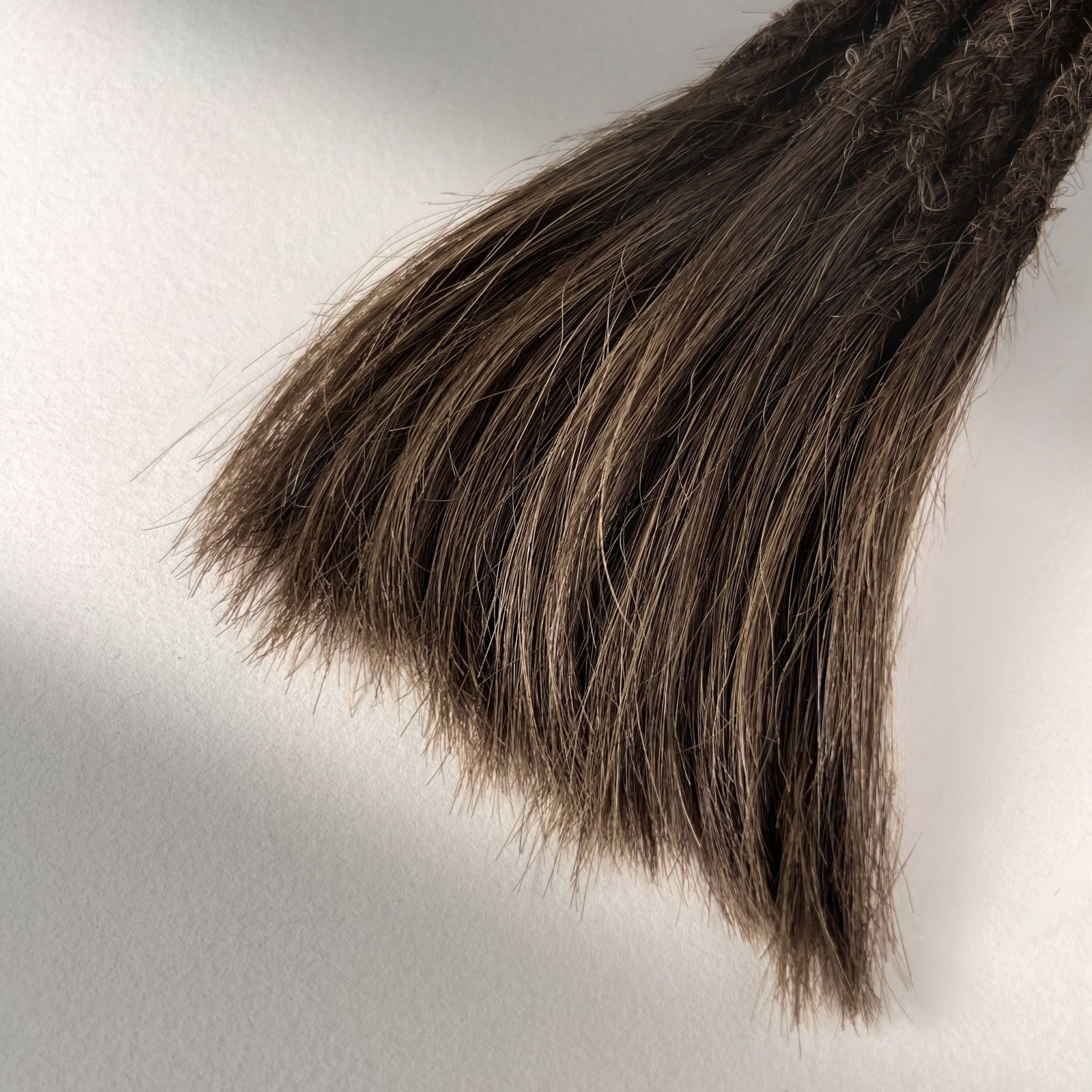 Tip detail of straight loc extensions with open ends in Medium Brown.