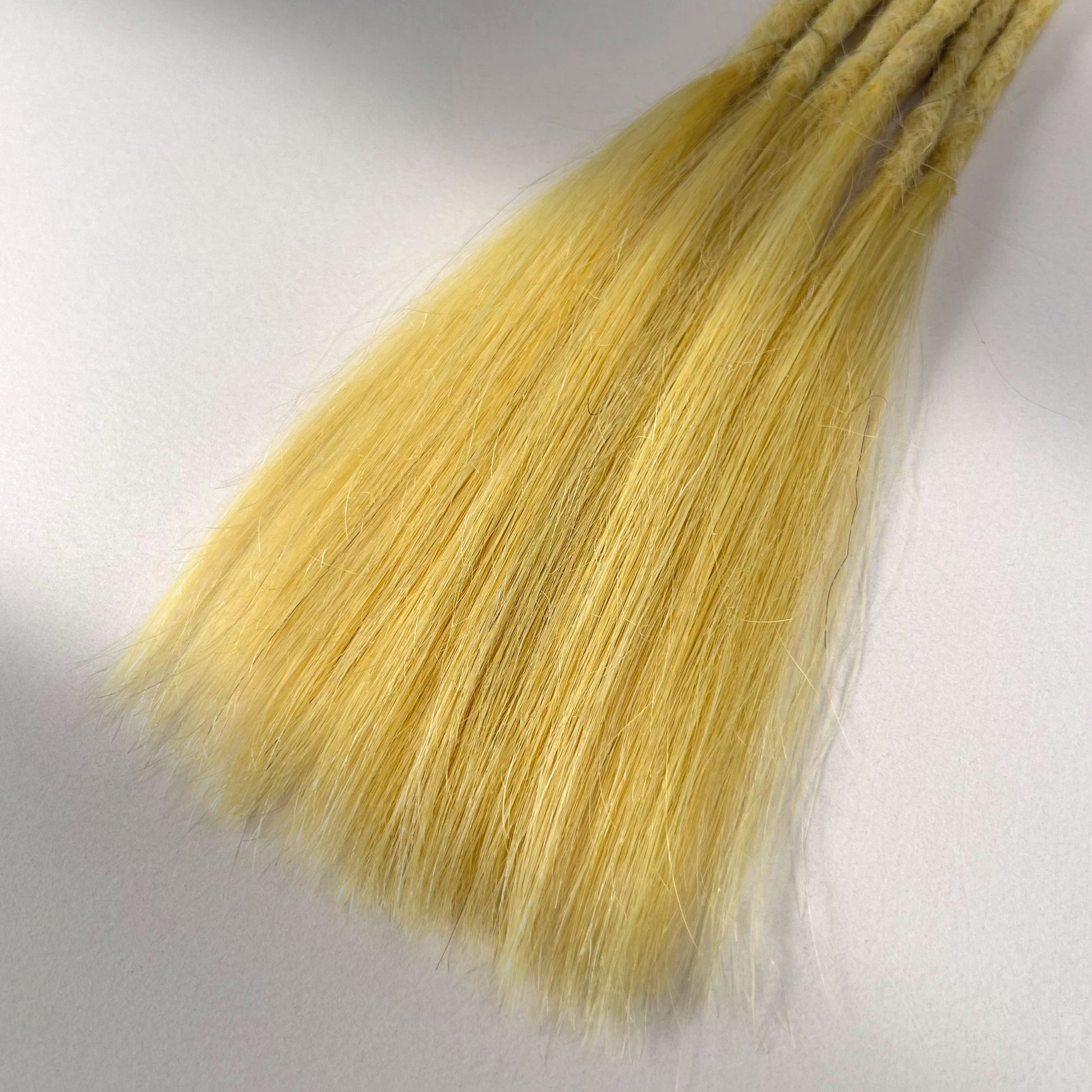 Tip detail of straight loc extensions with long loose ends in Soft Ochre.