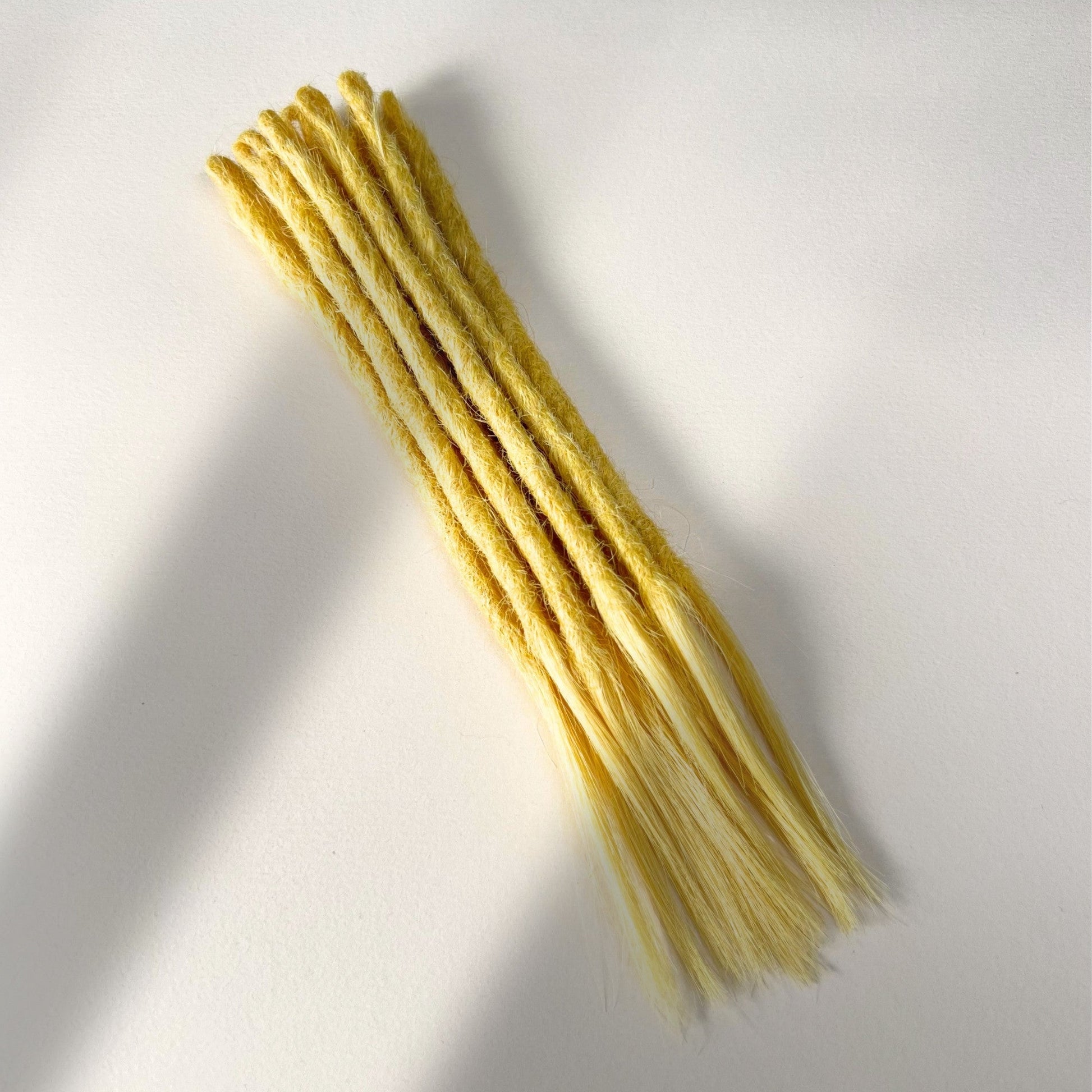Full view of temporary single-ended straight loc extensions with open ends in Soft Ochre.