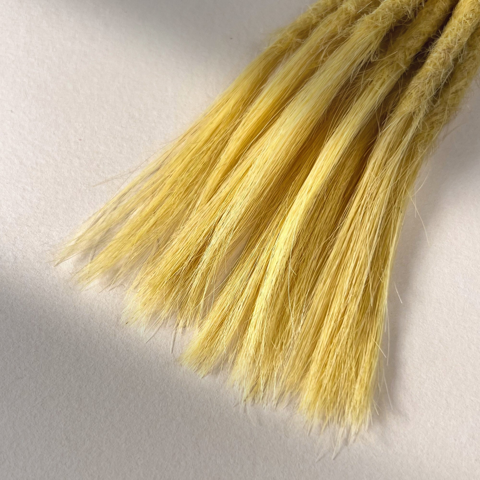 Tip detail of straight loc extensions with open ends in Soft Ochre.